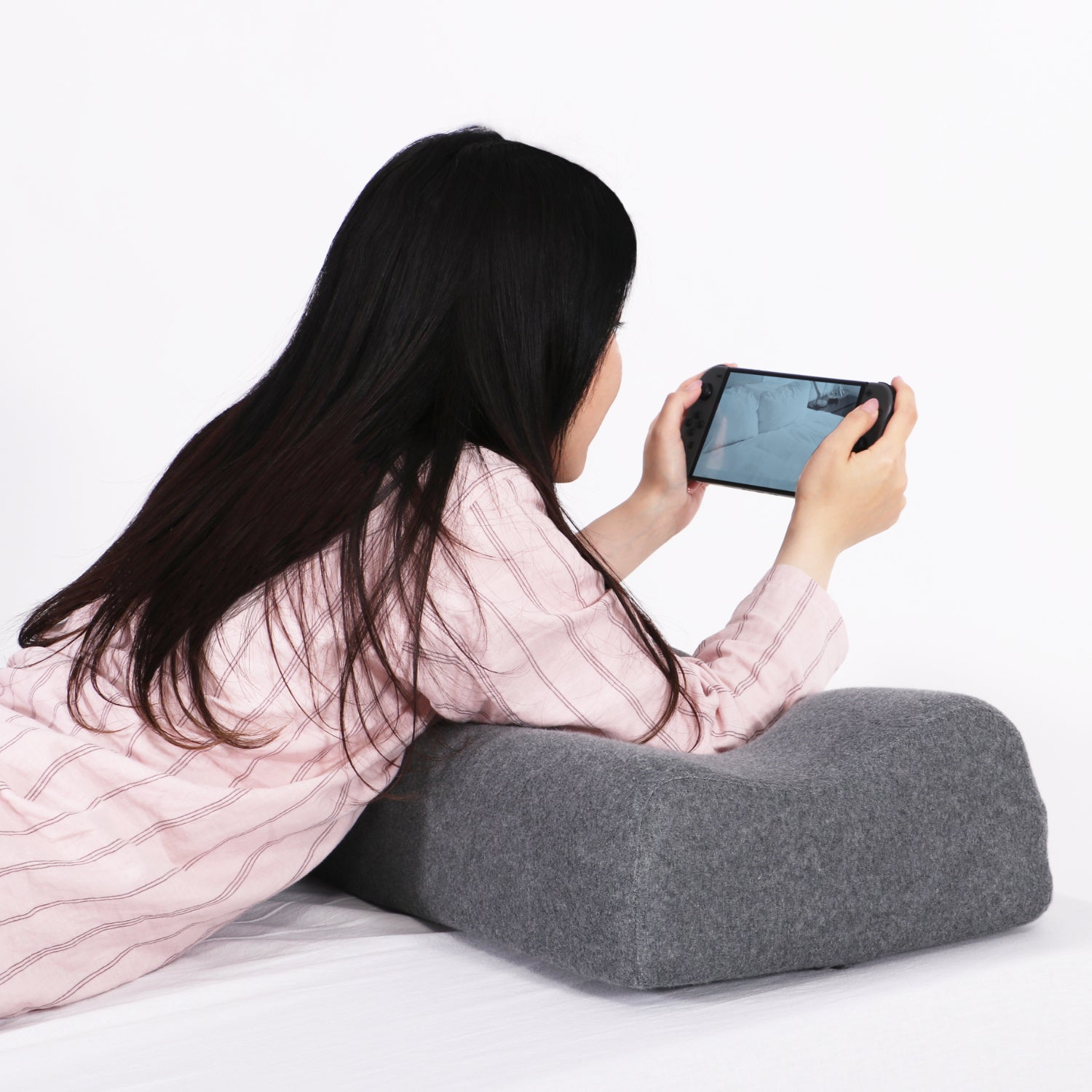 ゲーミングロングピローを使ってうつ伏せで携帯ゲーム機をプレイする様子