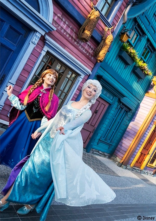 仲睦まじく歩くアナとエルサ。© Disney